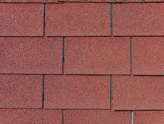 Текстура на тъмно червеникаво-кафяв керемиден покрив с правоъгълна форма, изработен от смес от битум, гума и рециклирана пластмаса