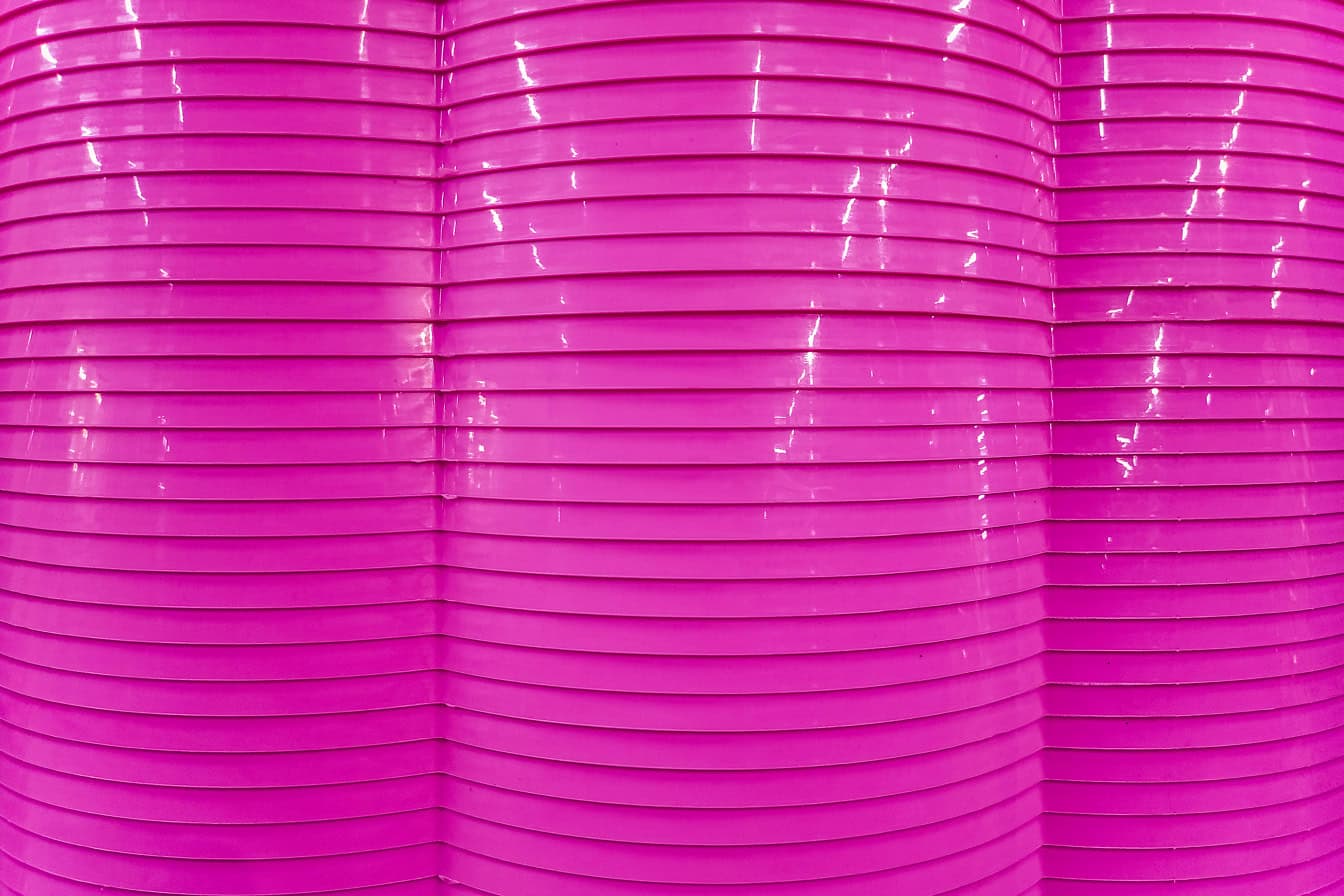수평선이 있는 분홍색 물결 모양의 광택 있는 플라스틱 표면의 질감