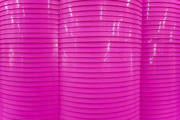 Tekstura różowej, falistej, błyszczącej powierzchni z tworzywa sztucznego z poziomymi liniami