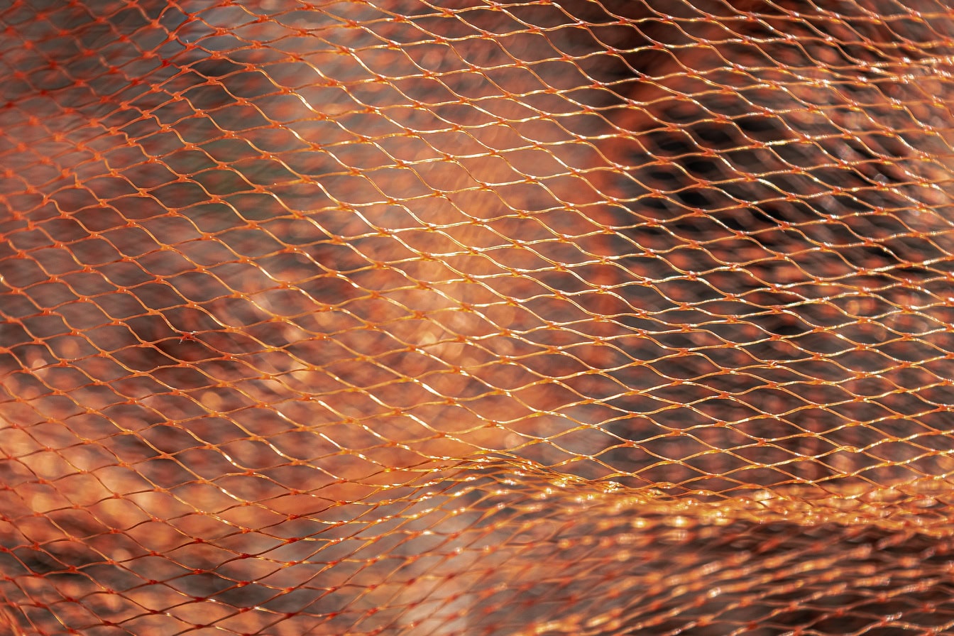 Texture di una rete giallo-arancio in cloruro di polivinile, un materiale vinilico termoplastico ad alta resistenza