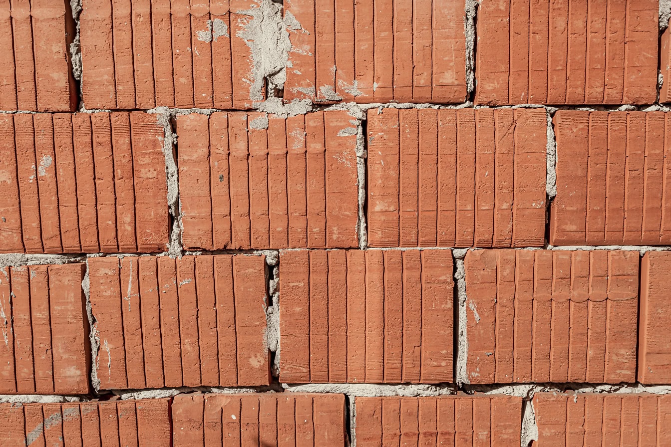 Texture d’un mur avec des blocs de terre cuite d’argile rougeâtre avec des lignes verticales dessus