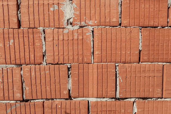 Struktur av en vägg med rödaktig lerterrakottablock med vertikala linjer på dem