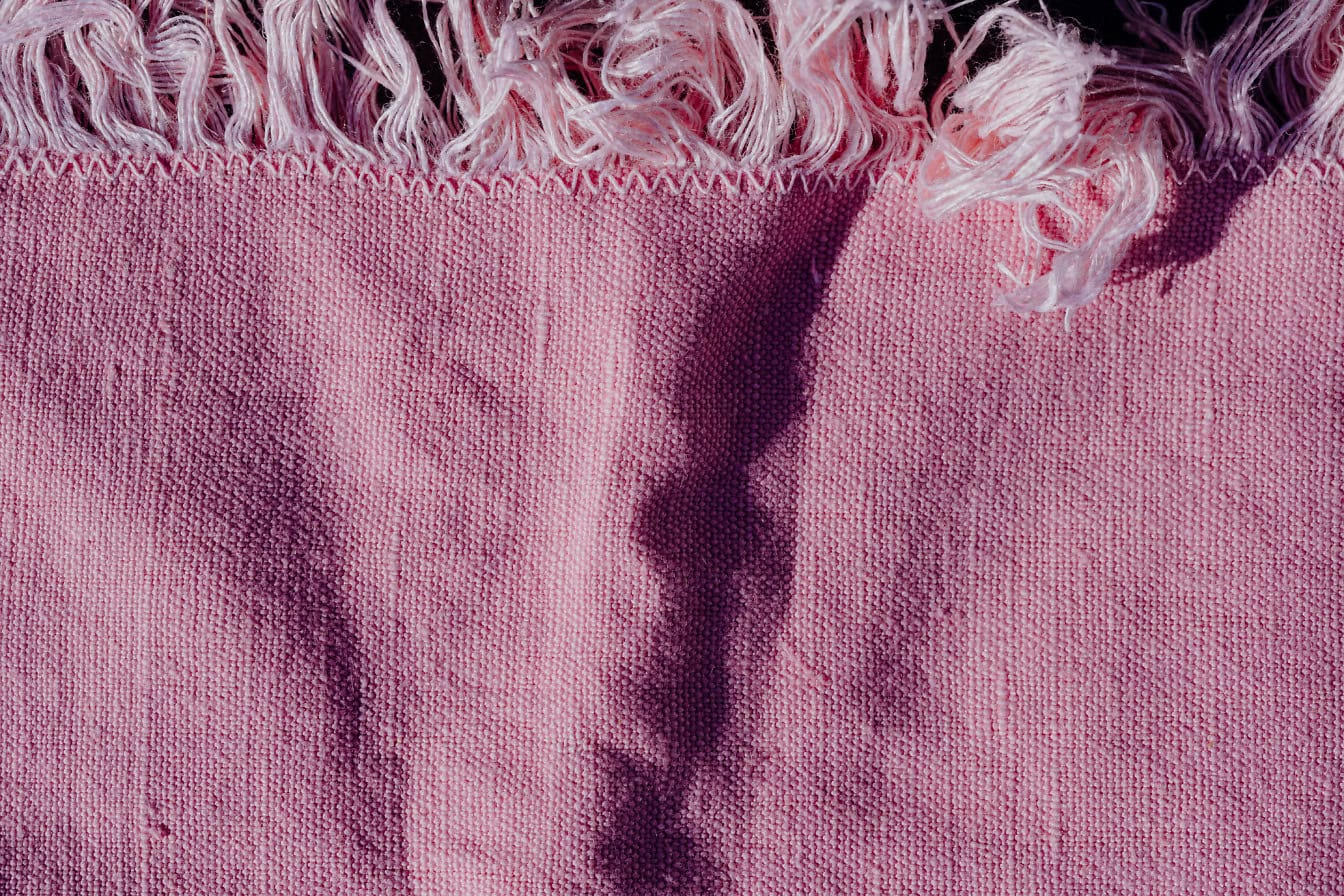 Uma textura de um tecido de franjas rosadas de algodão