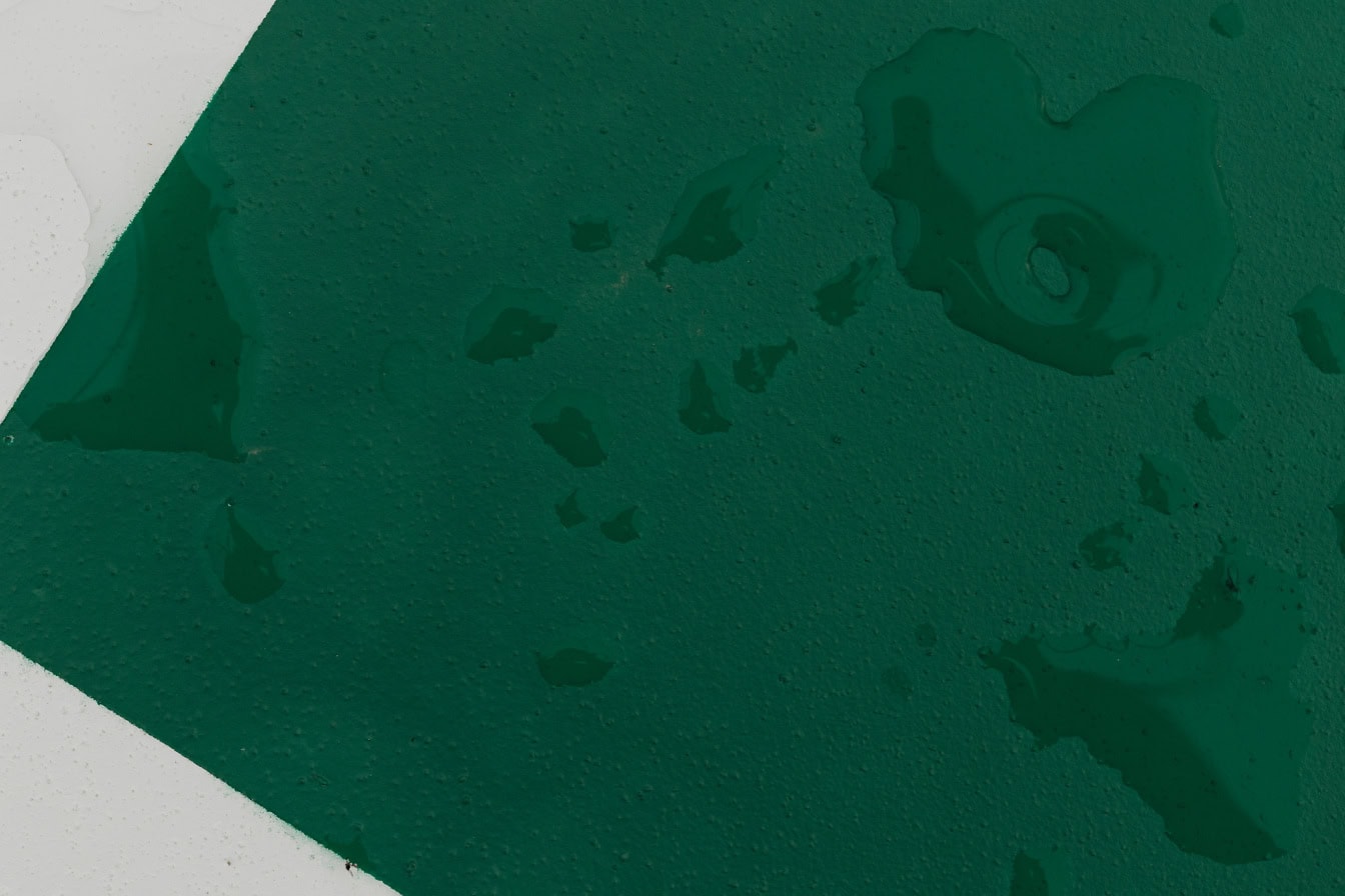 물방울이 있는 금속판에 짙은 녹색과 흰색 페인트
