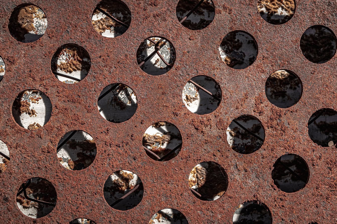 Tekstur permukaan logam berkarat dengan lubang melingkar