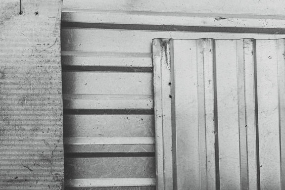Чорно-біла фактура старого алюмінієвого металевого листа поруч з глянцевими панелями з оцинкованого заліза з вертикальними і горизонтальними лініями