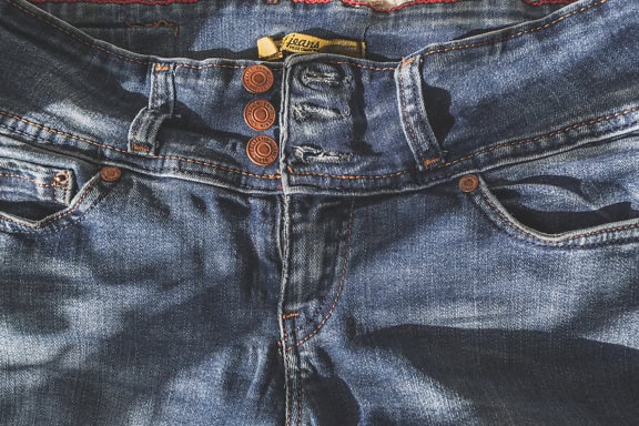 Zbliżenie pary dżinsów, faktura niebieskich bawełnianych spodni w cieniu