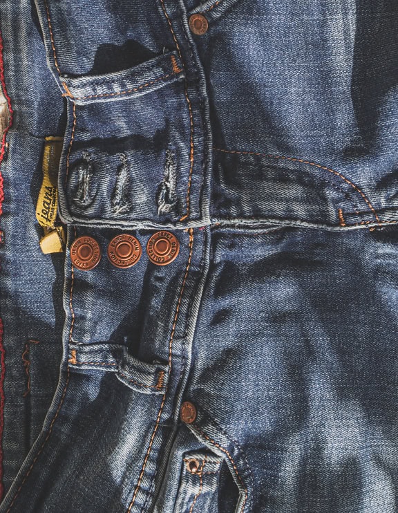 Un par de jeans azul oscuro, un pantalón azul con tres botones de cobre