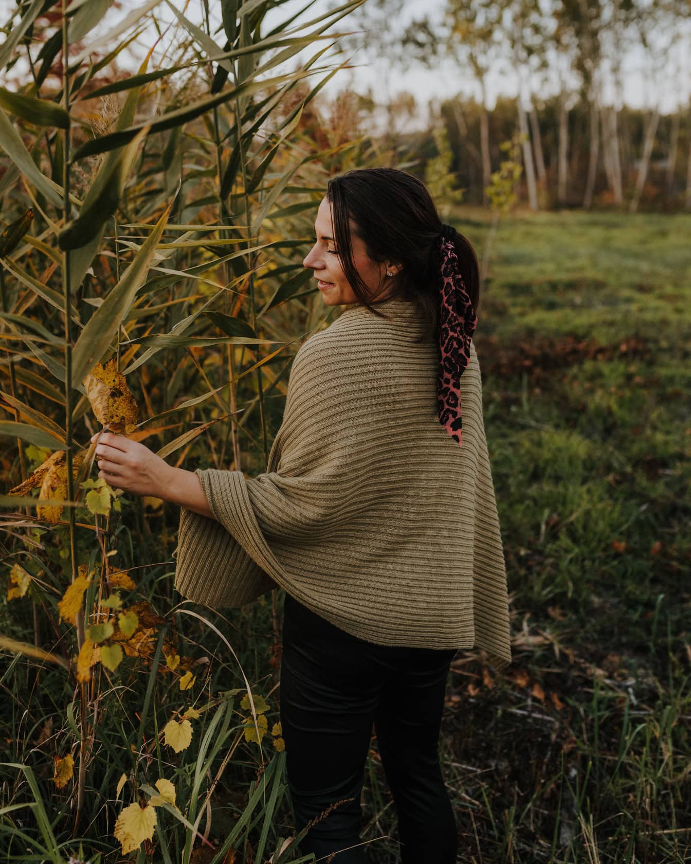 Chân dung một người phụ nữ mặc áo poncho thủ công đứng trên cánh đồng bên đám lau sậy