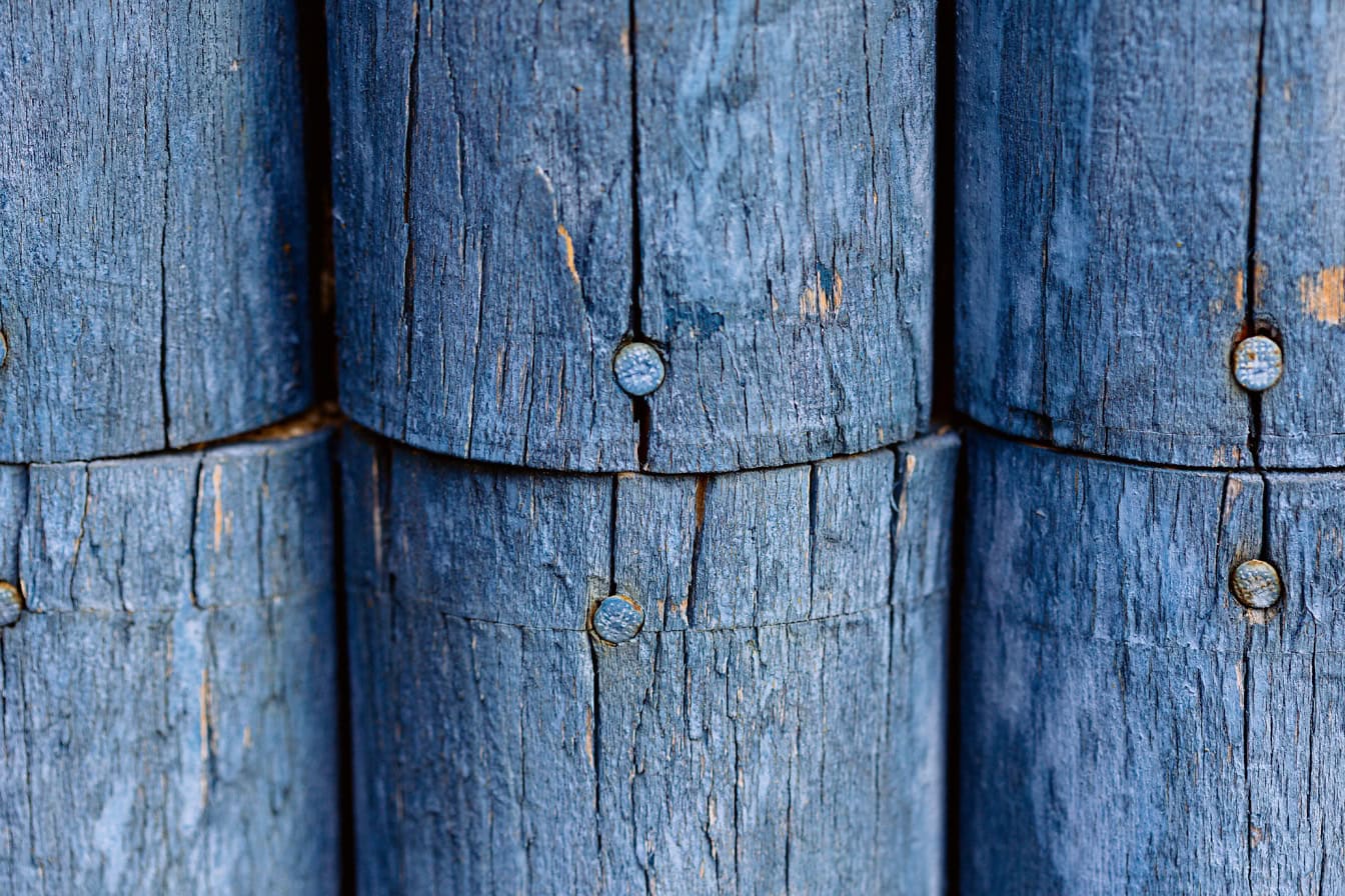 Textura de tábuas de madeira arredondadas pintadas em azul escuro com pregos de metal