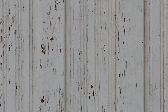 Textura dřevěného panelu s vertikálně naskládanými prkny se starou bílou barvou, která se odlupuje od dřeva