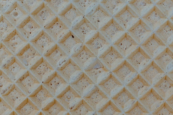 Textuur van een geelachtig bruine wafel met geometrisch patroon van een ruit