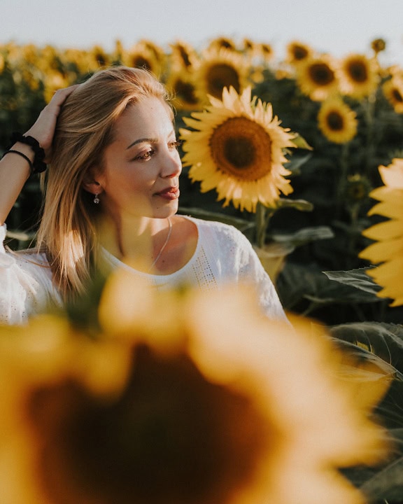 Портрет на красива млада блондинка в поле от слънчогледи