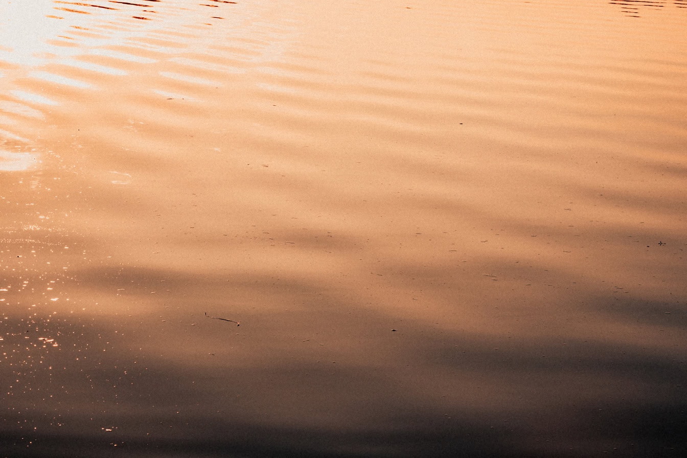 Отражение солнечных лучей на поверхности воды с волнами на закате
