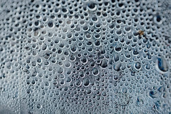 Textur av vattendroppar på en genomskinlig glasyta med detaljer av många små bubblor