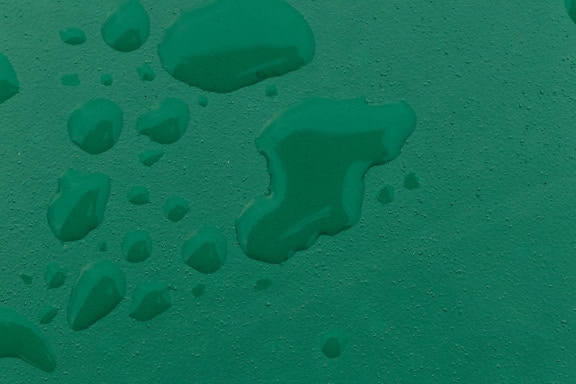 Tekstur av mørkegrønn overflate med vanndråper