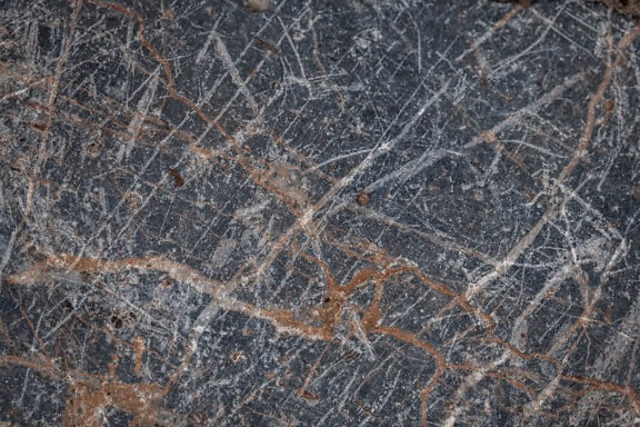 Povrchová textúra tmavého žulového kameňa so stopami železnej rudy v ňom