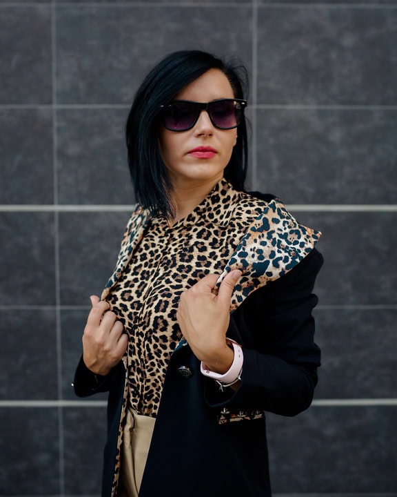 Portrét podnikateľky so slnečnými okuliarmi a košeľou s leopardím vzorom pod čiernou bundou