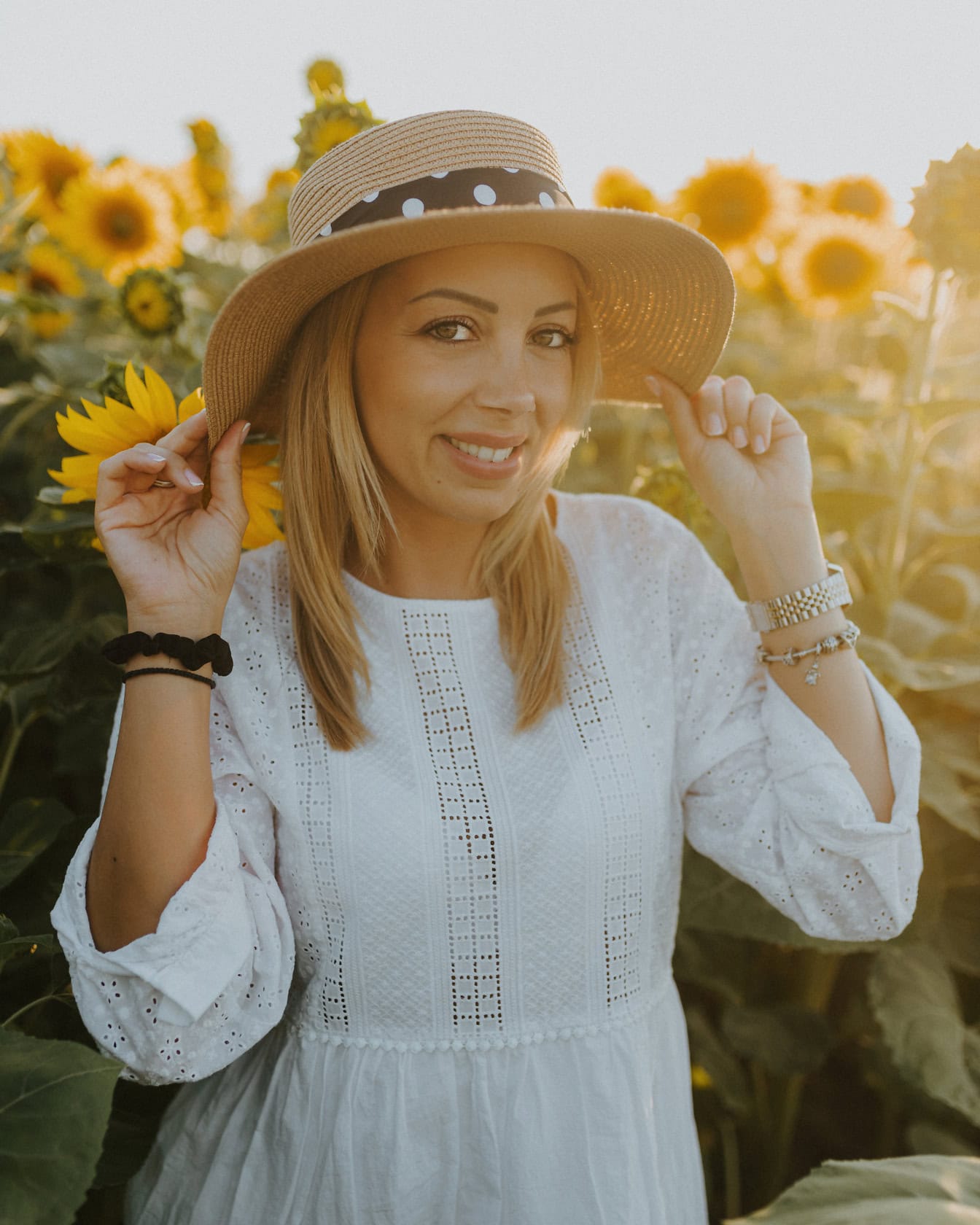 Profesionální portrétní fotografie dobře vypadající ženy ve slaměném klobouku na poli slunečnic