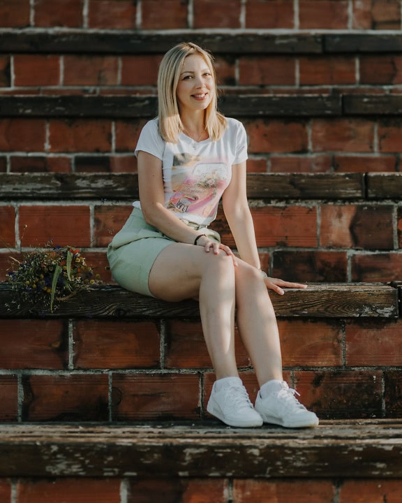 Portrait of a handsome smiling woman sitting on a brick staircase