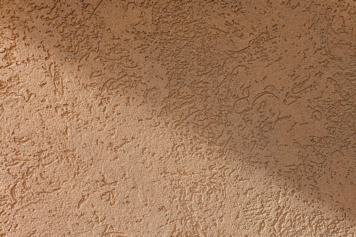 斜めの影のあるオレンジがかった茶色の壁のデミットファサードの質感