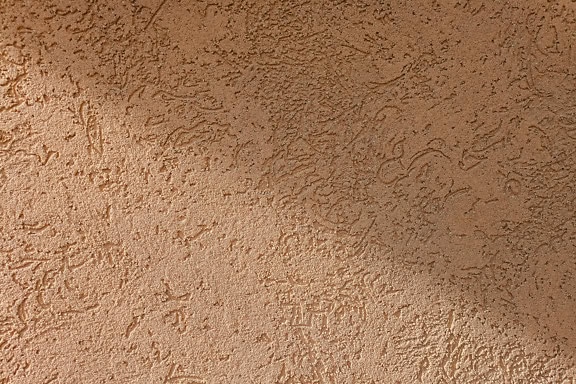 Textura de uma fachada demit em uma parede na cor laranja-acastanhada com uma sombra diagonal