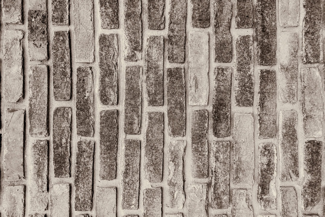 Sepia photo of texture of an old brick wall with vertically stacked bricks and thick cement