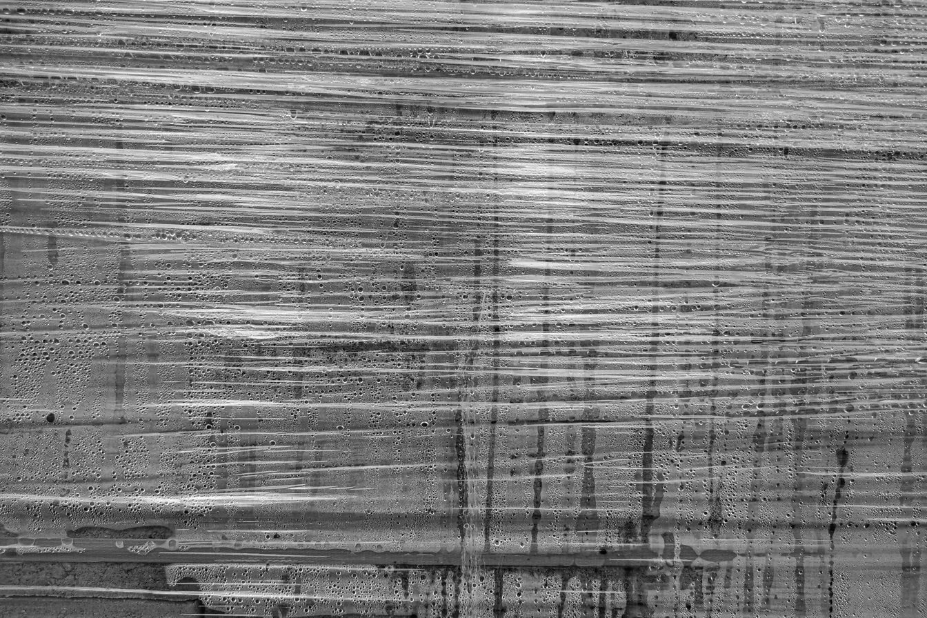 Altında su damlaları bulunan şeffaf bir naylon sargının siyah beyaz dokusu