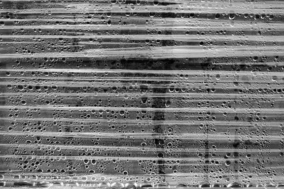 Black and white texture of a transparent plastic wrap with waterdrops underneath it