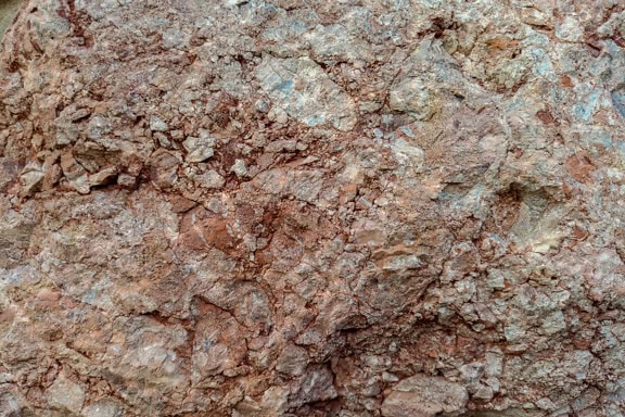 Nærbillede tekstur af en ru rødbrun granitsten
