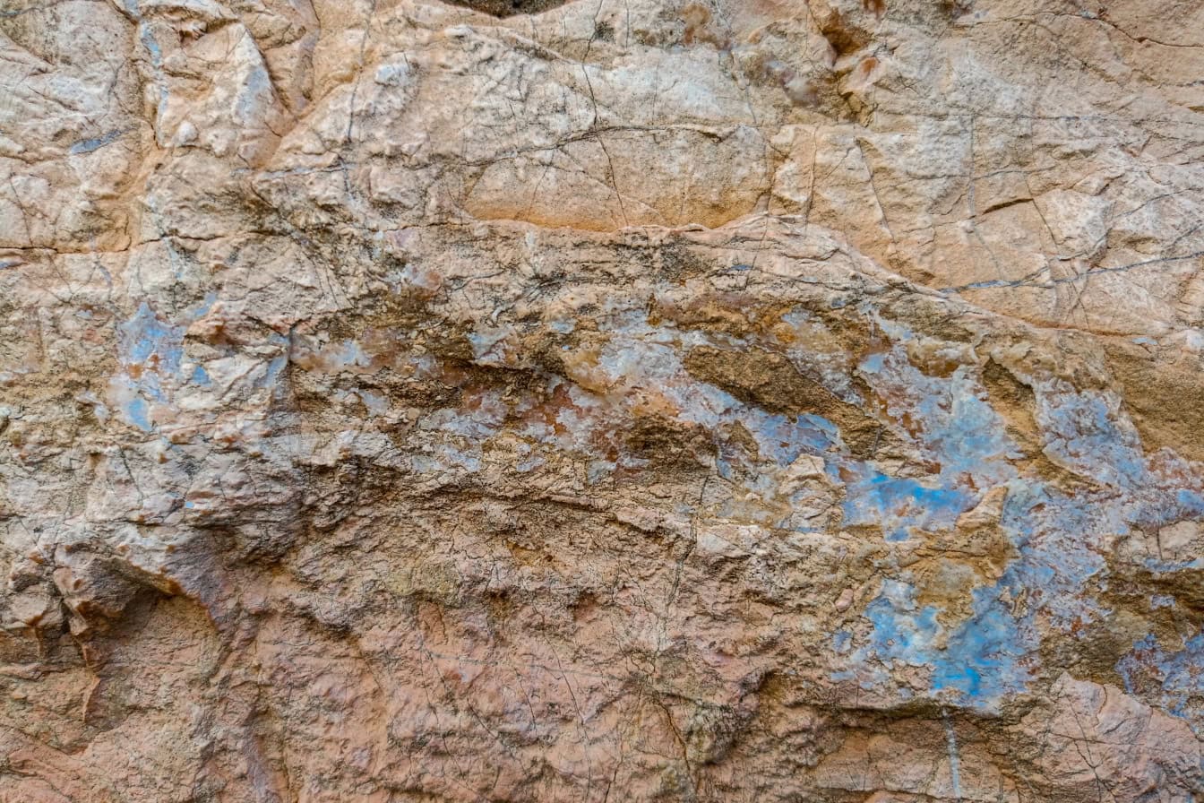 Tekstur av en gulbrun granittstein med spor av blått mineral i den