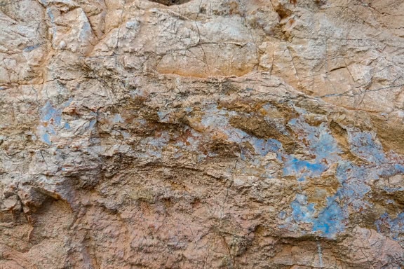 Kellertävänruskean graniittikiven rakenne, jossa on jälkiä sinisestä mineraalista