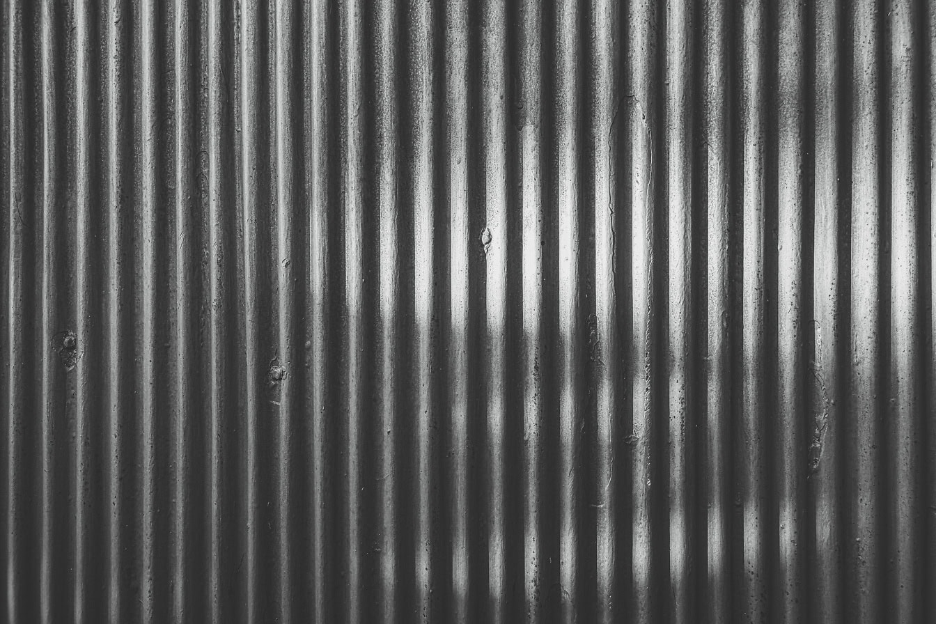 Texture en noir et blanc d’une vieille tôle rouillée avec des lignes verticales dans l’ombre