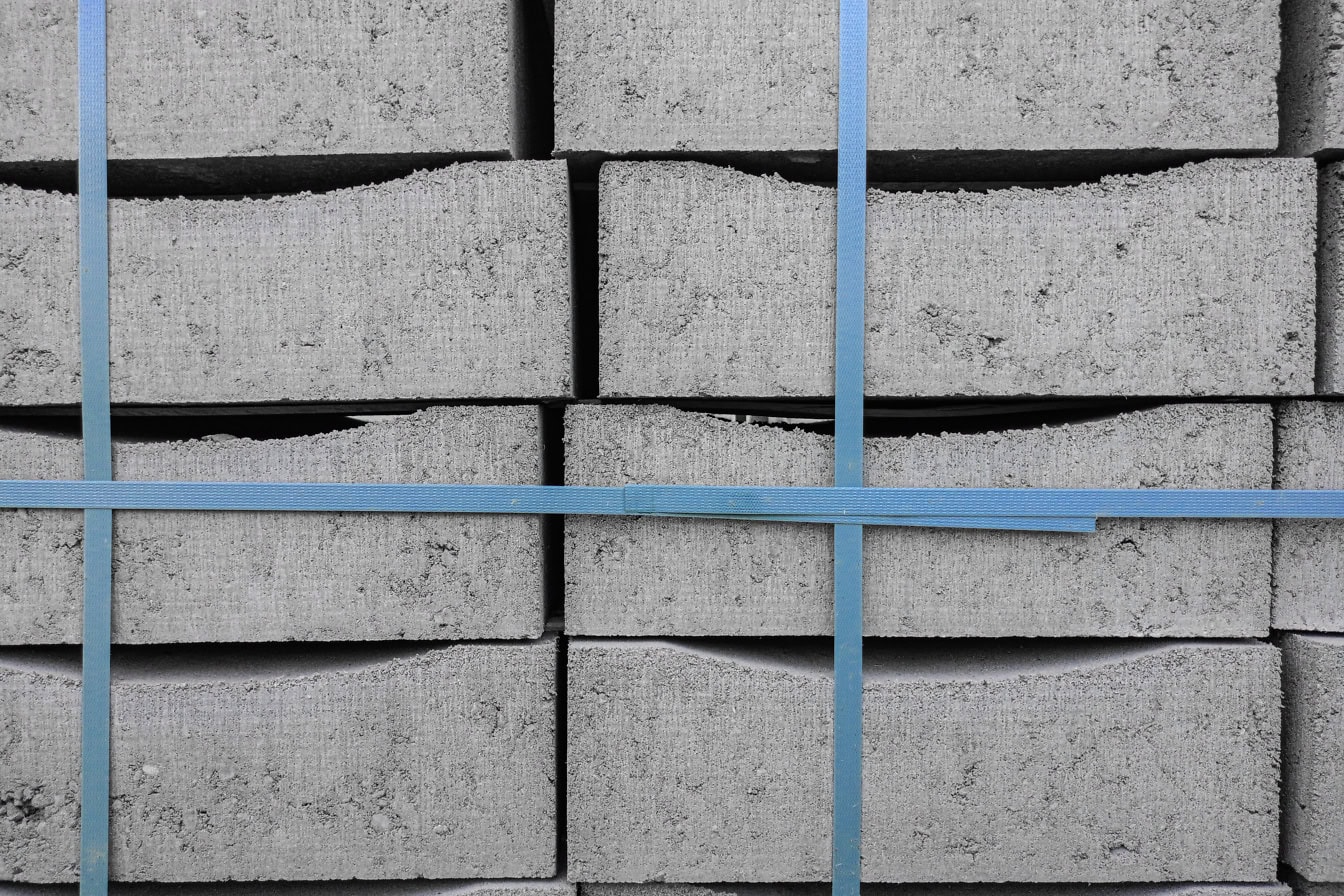 Tekstur av en stabel med betongblokker bundet med et blått plastbånd