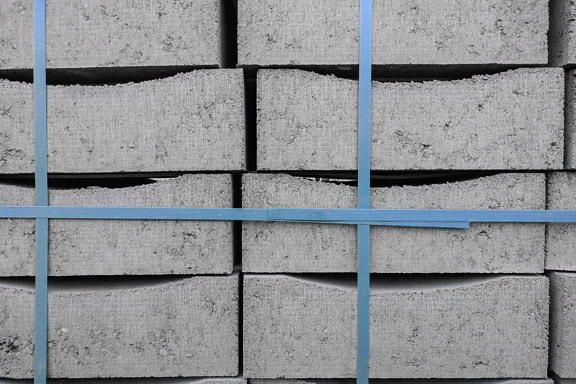 Texture of a stack of concrete blocks tied with a blue plastic band