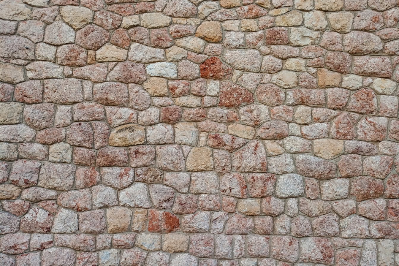 Textura de una pared hecha de piedras de granito rojizo y marrón amarillento
