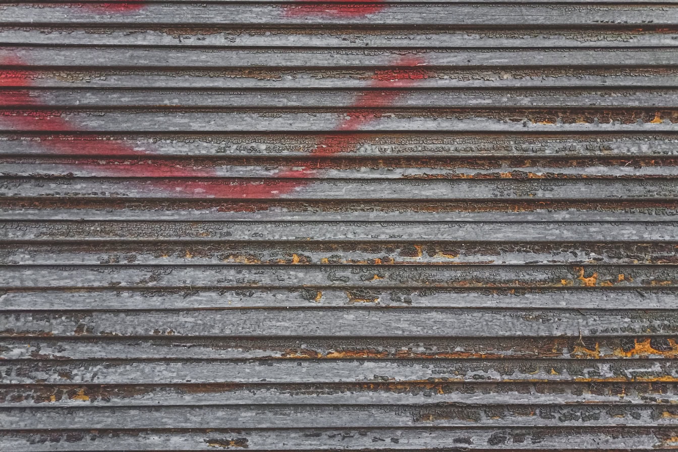 赤みを帯びたスプレーの痕跡と表面から剥がれた古い茶色のペンキのある古い木製のブラインドの質感
