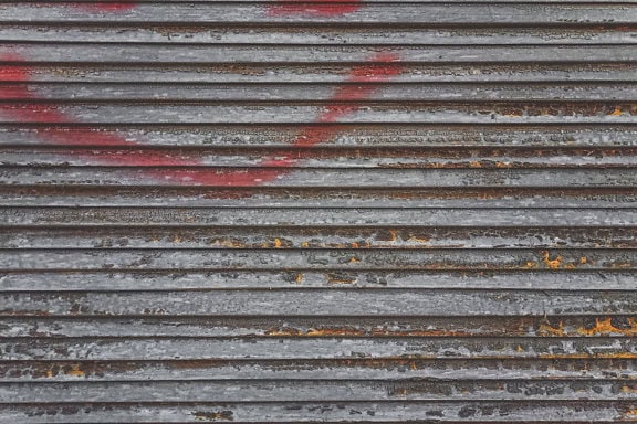 Tekstur av et gammelt trevindu persienner med spor av rødlig spray og en gammel brun maling som skreller av fra overflaten
