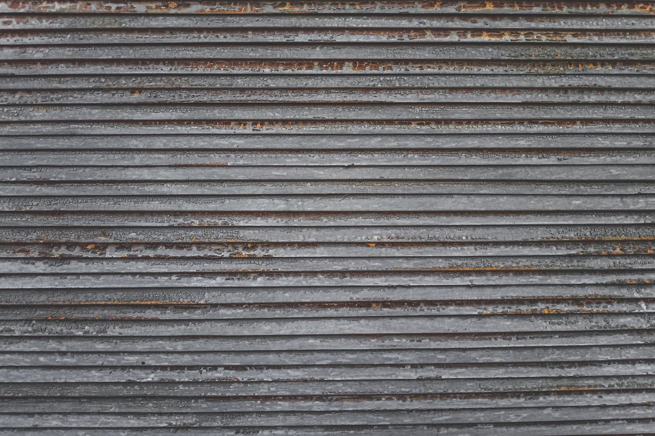 Texture d’un vieux store en bois avec des lignes horizontales et des traces de peinture brunâtre qui se décollent de la surface