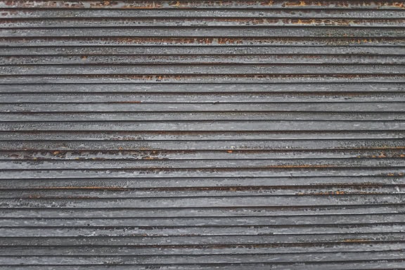 Tekstur av et gammelt trevindu persienner med horisontale linjer og spor av brunaktig maling som skreller av fra overflaten