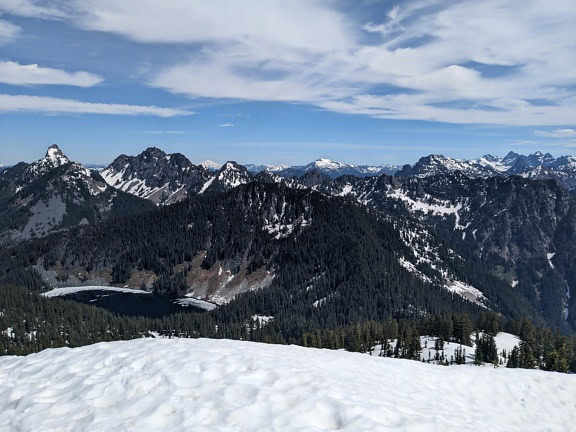 Pohled na Žulovou horu ve Washingtonu se zasněženými vrcholky hor a se stromy a jezerem