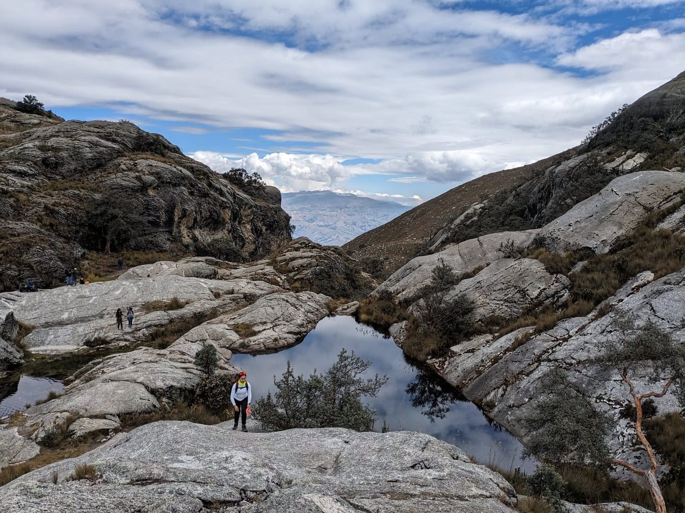 페루의 자연 공원에 있는 산 한가운데에 있는 작은 산 호수의 바위 기슭에 한 산악인이 서 있다
