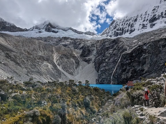 Excursioniști în parcul național Huascaran din Cordillera Blanca din Peru, cel mai înalt lanț muntos tropical din lume, cu un lac și munți înzăpeziți