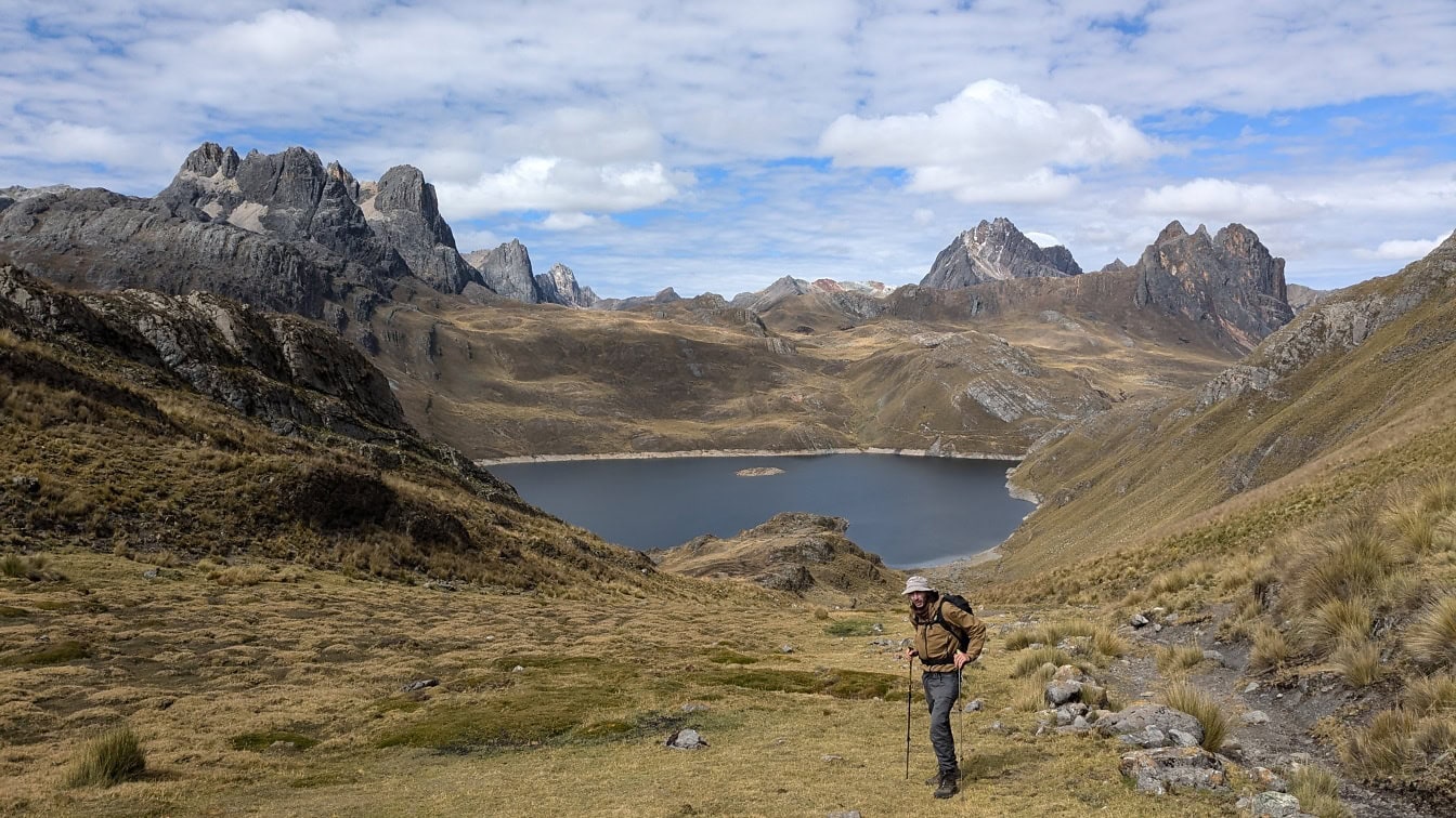Hiker standing in the mountains at the Paso de Carhuac pass in the Cordillera Huayhuash mountain range in Peru