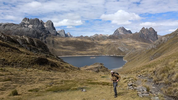 Turista stojaci v horách pri priesmyku Paso de Carhuac v pohorí Cordillera Huayhuash v Peru