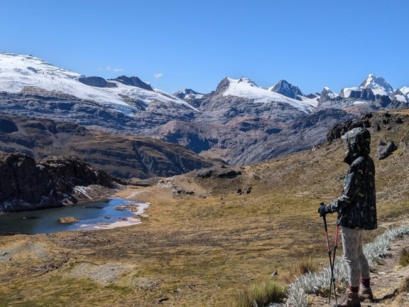 계곡에 서서 페루의 Cordillera Huayhuash 산맥에서 장엄한 설산을 내려다보고 있는 사람