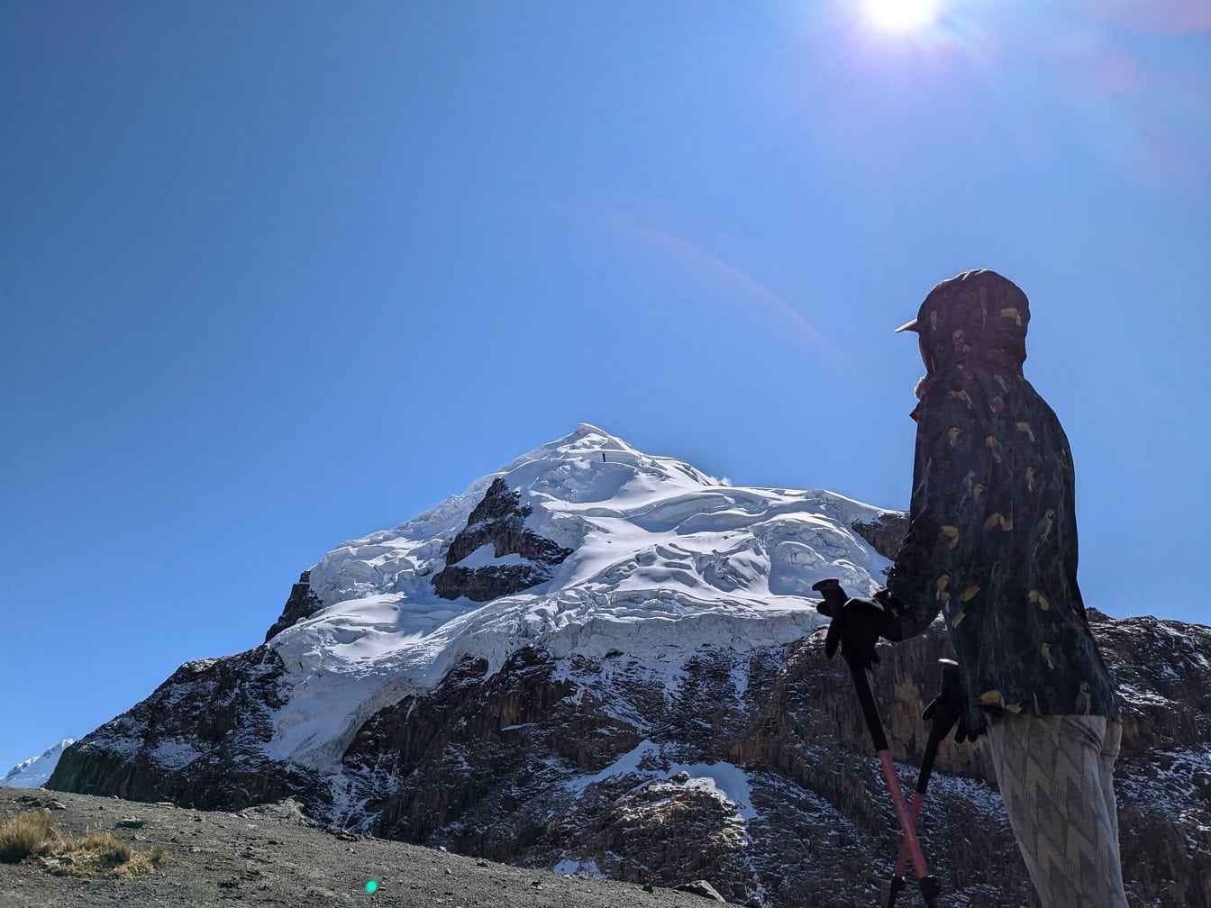 Hiking in front of a snowy mountain with bright sunrays from a blue sky