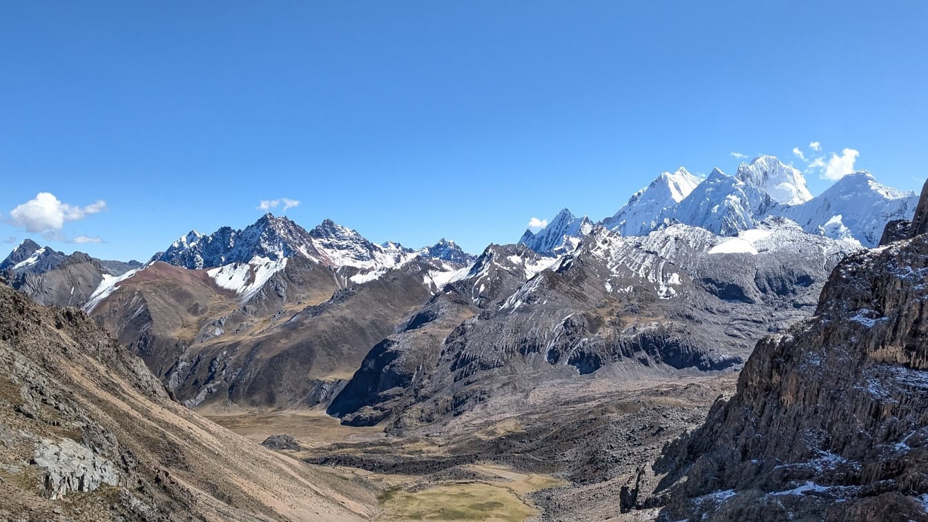 Údolí se zasněženými horami s modrou oblohou v pohoří Cordillera Huayhuash v peruánských Andách v Jižní Americe