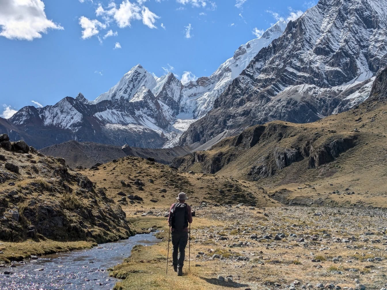 Mand vandrer ved en bjergflod i bjergene i Peru