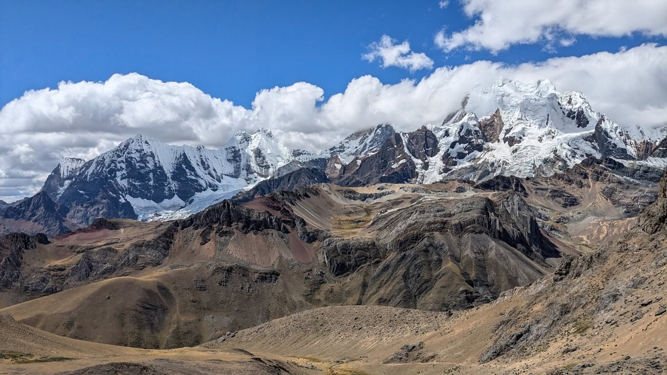 Luminen vuorijono sinisellä taivaalla ja pilvillä Cordillera Huayhuashin vuoristossa Andeilla, Perussa